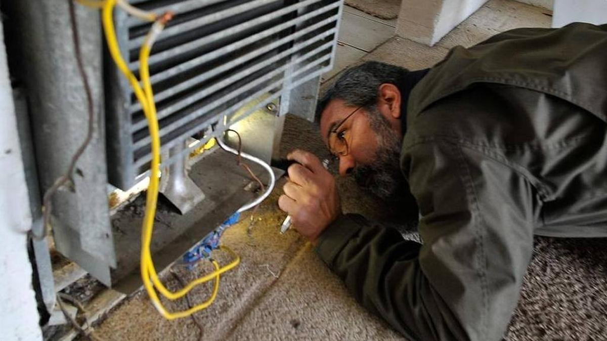 City code enforcement inspector John Tanksley examines a heater, improperly hooked up and with bare wires exposed, at an apartment complex earlier this year on East Clay Avenue.