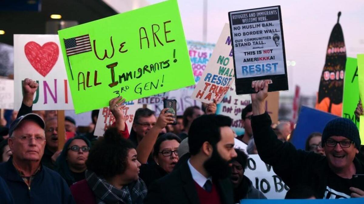 Hundreds of people hold signs in front of Fresno Yosemite International Airport during a protest Sunday evening, Jan. 29, 2017.