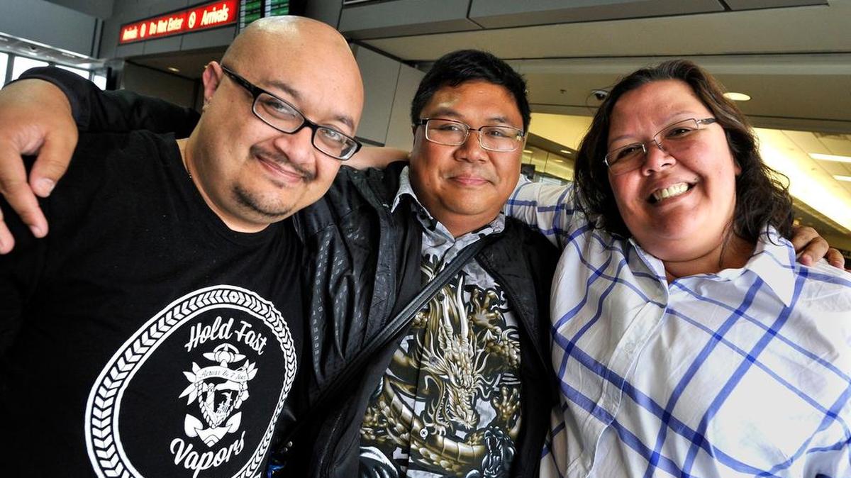 Mirasol Espinesen, right, with sibling Kirk Patience, left, pose for a photo with their “little” brother, Jorick Soriano, center, upon meeting him for the first time after he flew into Fresno Monday.