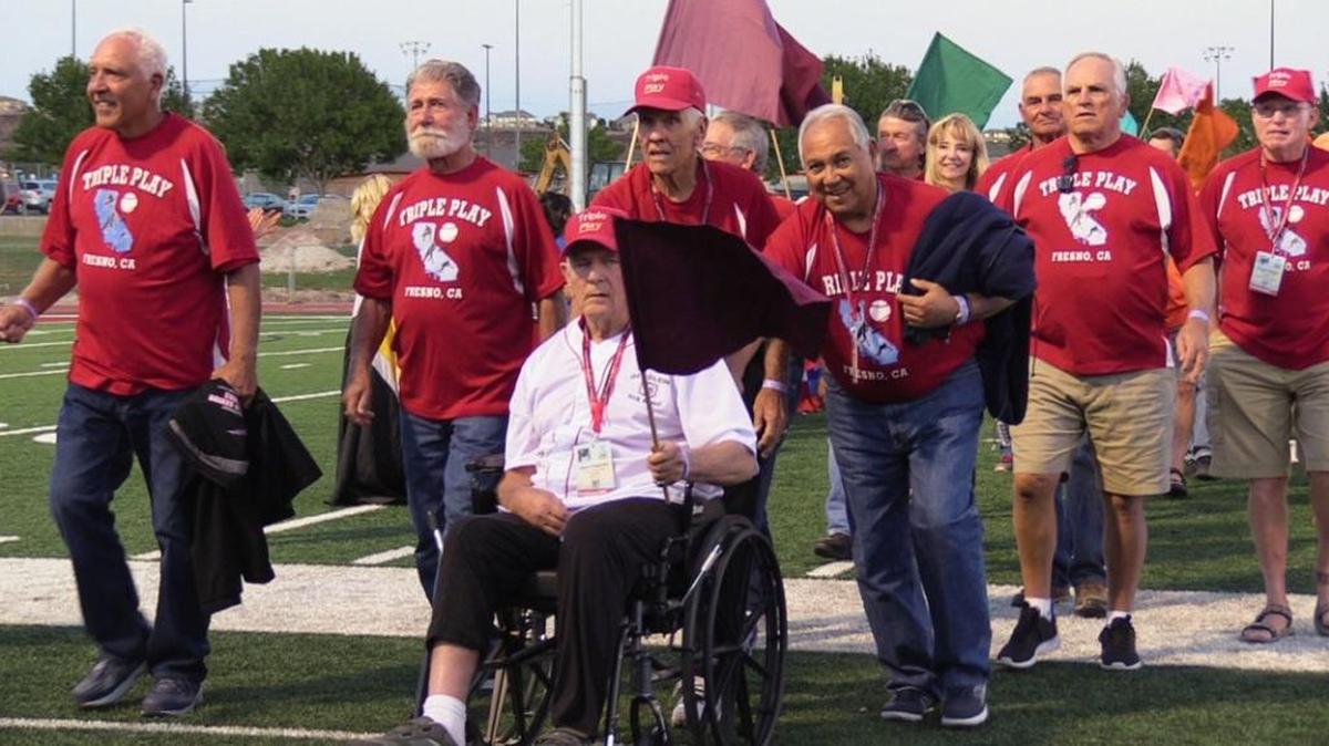 Glenn Fitzgerald of Fresno holds a flag as he's wheeled through the opening ceremonies of the 31st Huntsman World Senior Games at Legends Solar Stadium in Salt Lake City, Utah, Oct. 10.