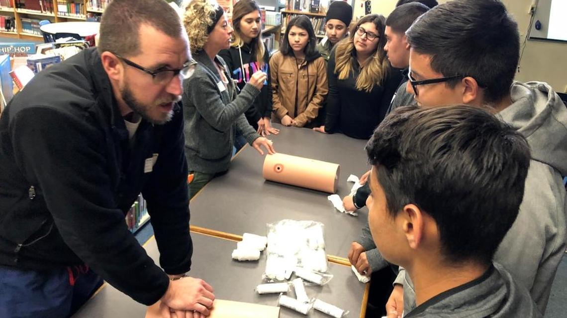 David Jeffcoach, M.D., a UCSF Fresno surgical critical care/acute care surgery fellow, shows Selma High School Doctors Academy students how to apply pressure to a wound.