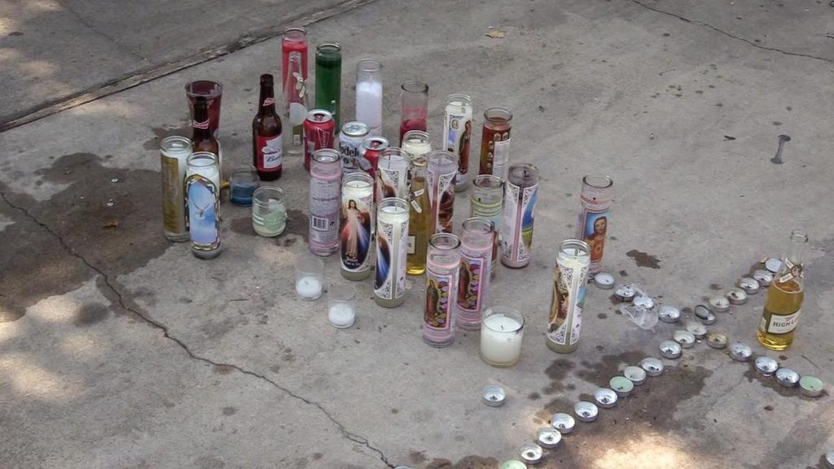 A memorial with candles and bottles of beer mark an area at West Shaw Estates on Wednesday, Aug. 1, 2018, where two men were shot and killed and a boy was injured in a shooting on Monday.