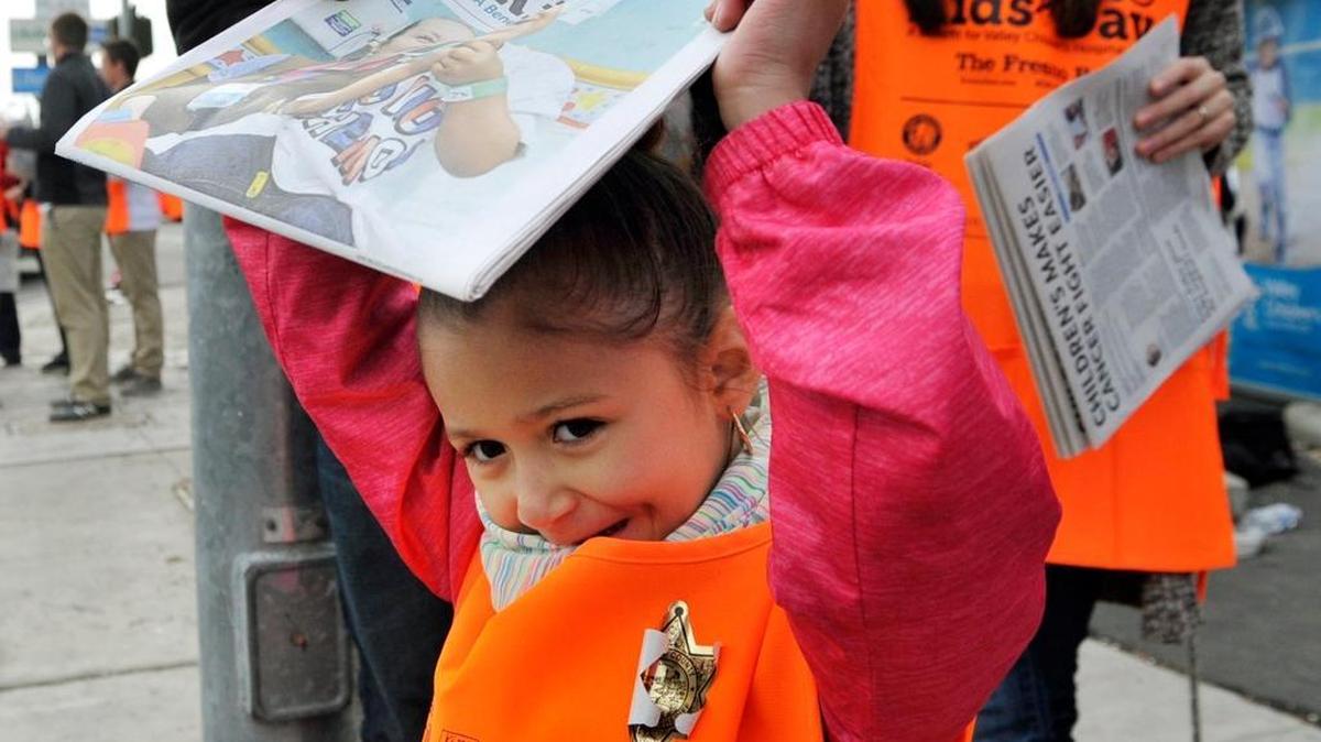 Naima Gutierrez of Merced, who has been cancer-free for three years, sells Kids Day papers at Blackstone and Shaw avenues last week.