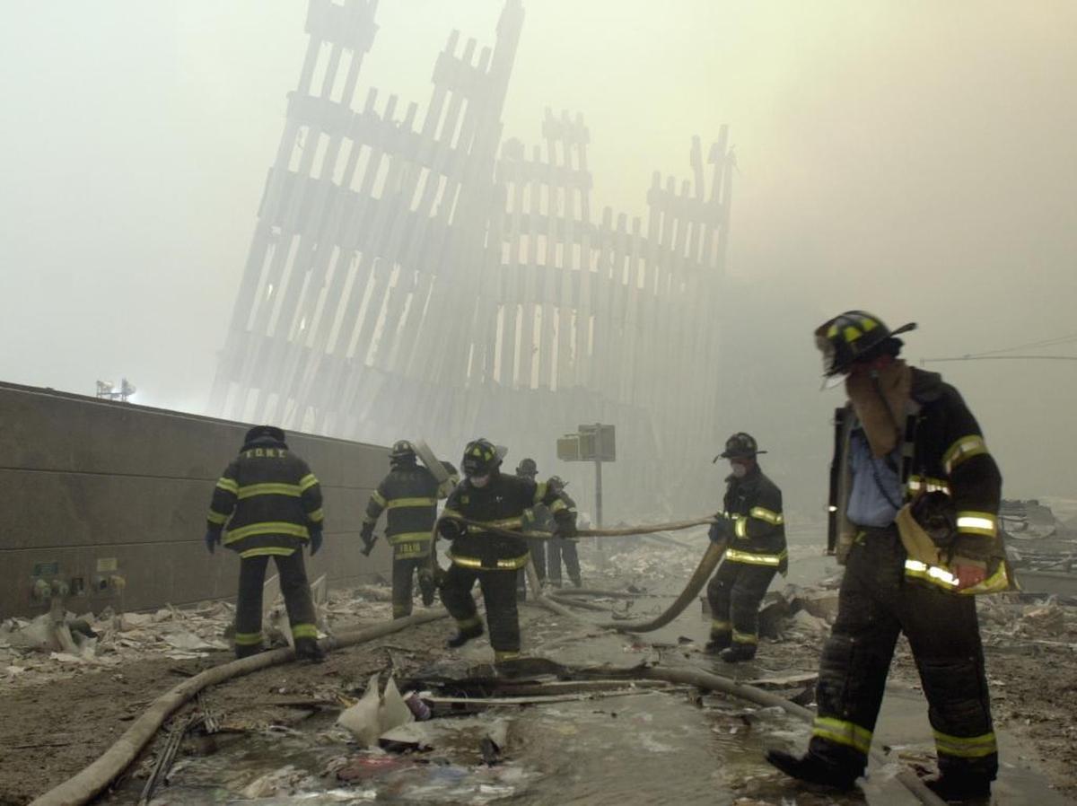 In this Sept. 11, 2001, photo, firefighters work beneath the destroyed mullions, the vertical struts which once faced the soaring outer walls of the World Trade Center towers in New York.