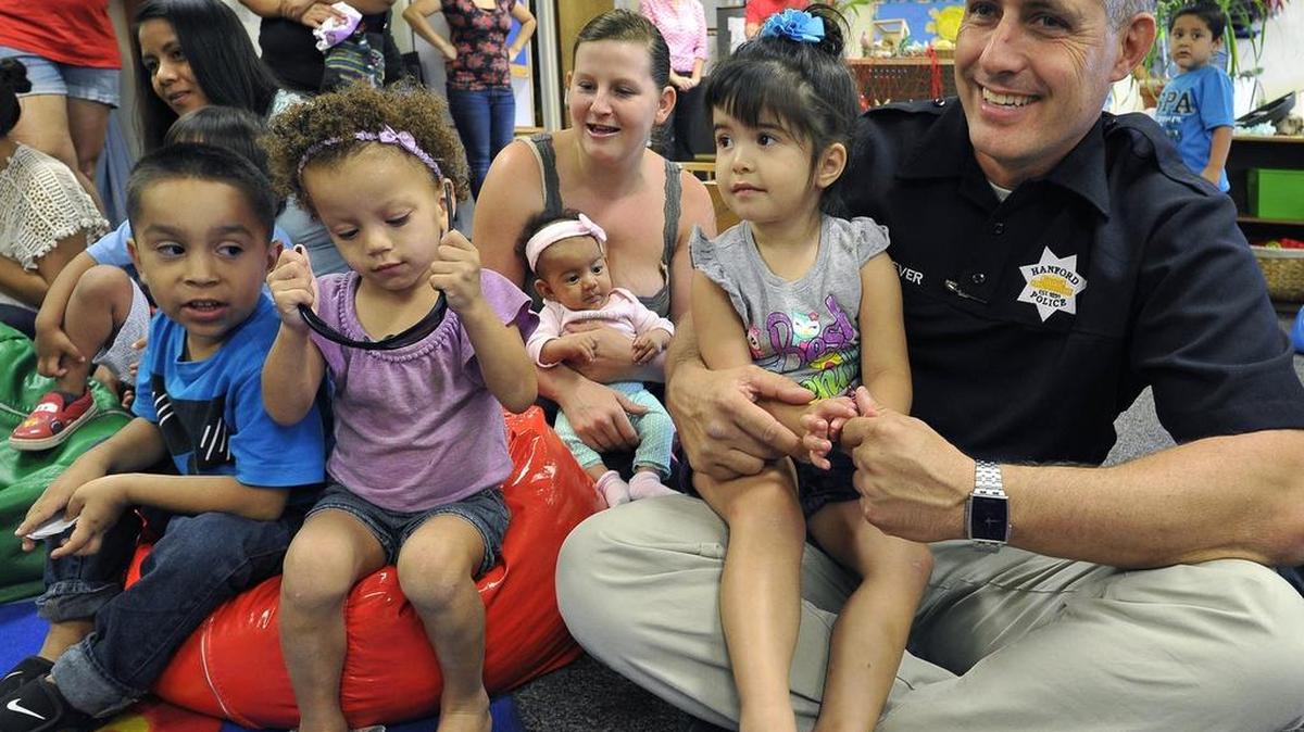 
Hanford Police Chief Parker Sever holds Anjolyna Freeman on his lap during a visits with children in the United Cerebral Palsy of Central California’s “Parent & Me” program during their story time. A play structure for the children at the center was recently stolen, but the Hanford Police Department led a fundraiser to replace the equipment.
