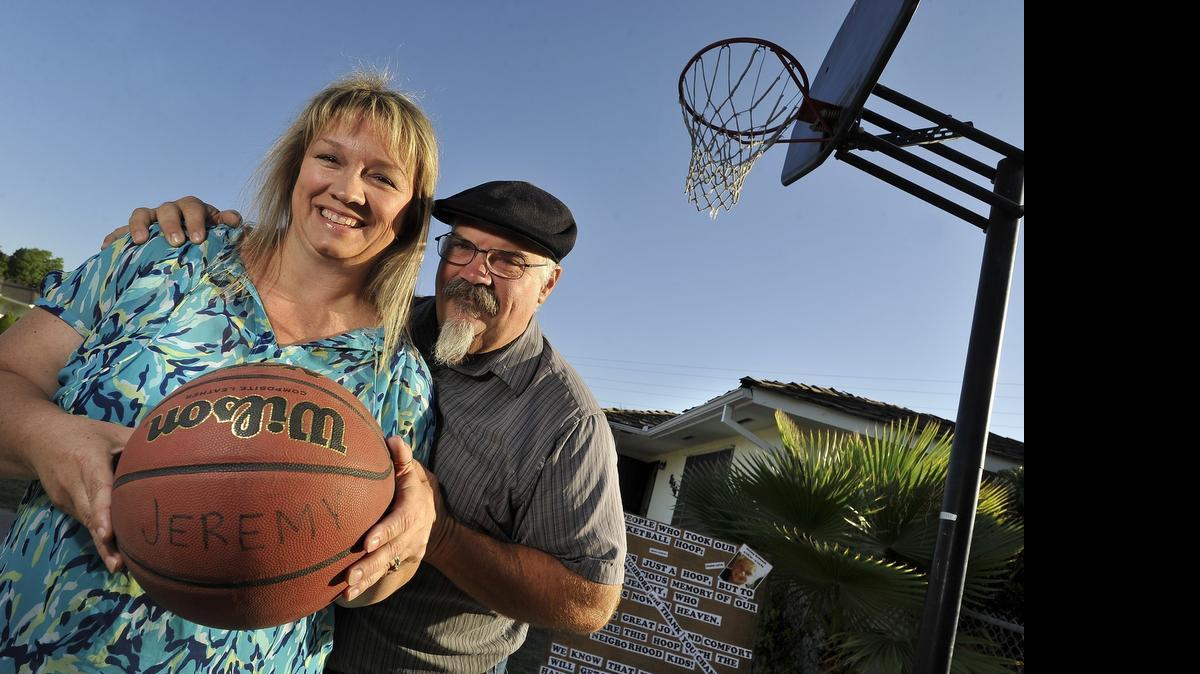 
Raelene and Randy Robinson with their late son Jeremy's name on a basketball, next to his beloved basketball hoop, which was stolen, then returned after a sign they placed in their driveway, with a plea for its return. Jeremy died 12 years ago, in a fatal crash at age 12. 
