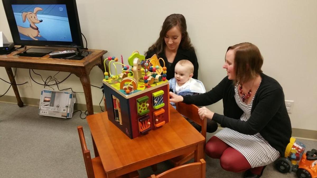 Kristina Hernandez, left, and Melissa Goss play with Goss’ baby Noah, 9 months old, in the new City Hall family room.