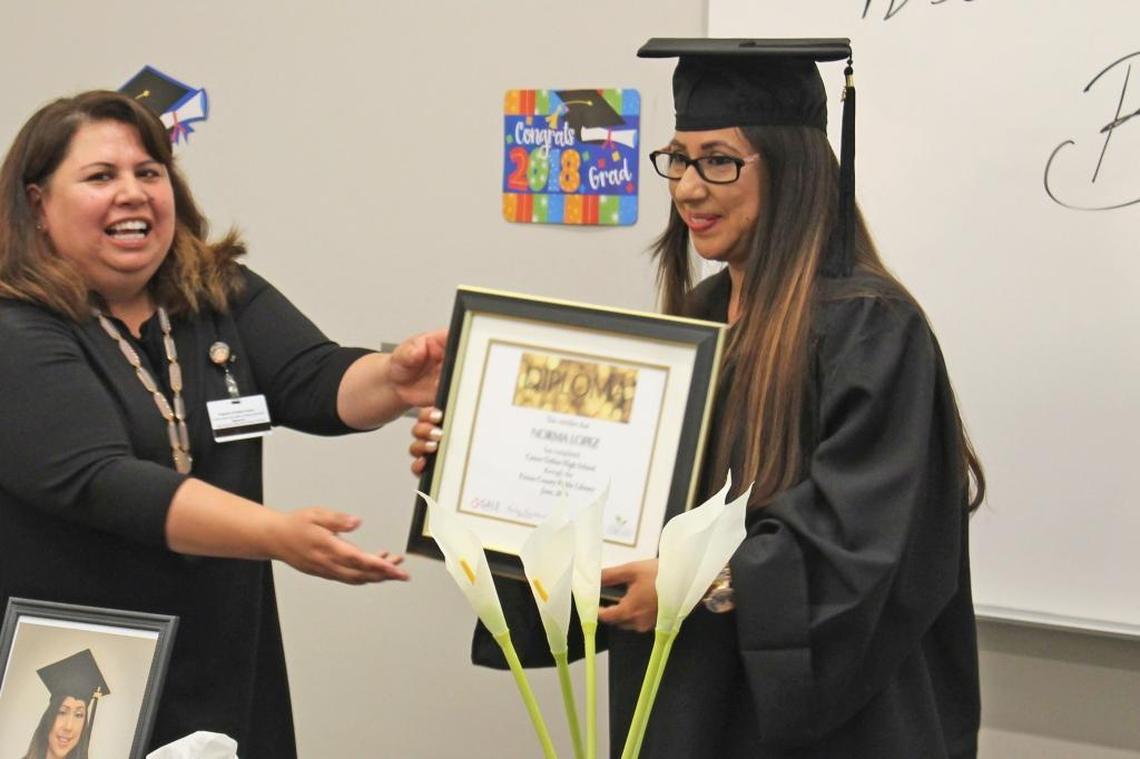 Norma Lopez receives her high school diploma from Deborah Bernal at a ceremony earlier this month. Lopez is the first graduate of the Fresno County Public Library’s career online high school program.