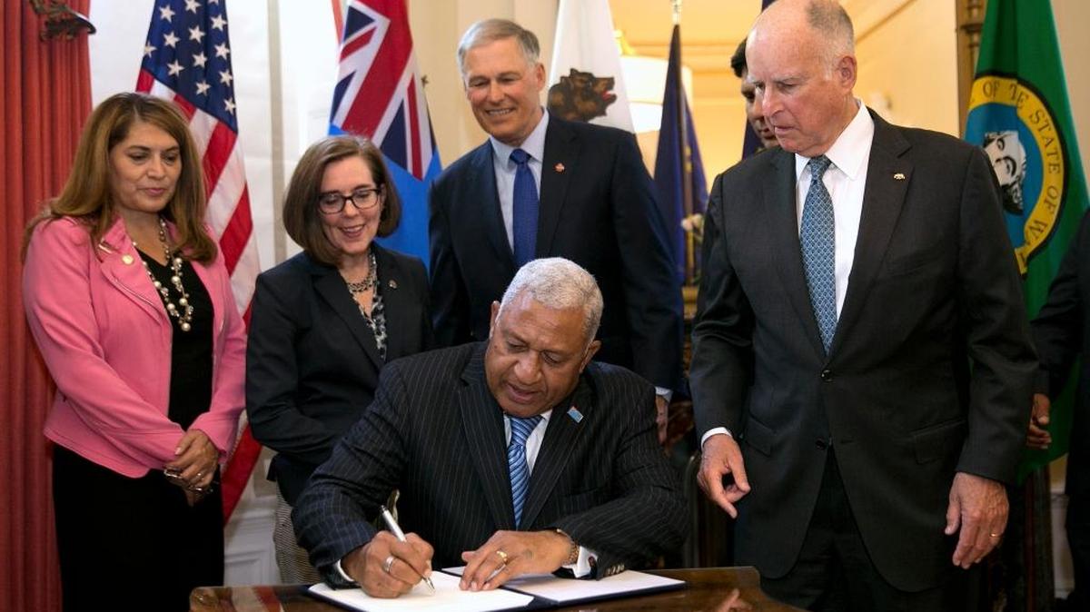 Gov. Jerry Brown, right, watches as Prime Minister of Fiji, Frank Bainimarama, signs a climate change accord on Tuesday at the Governor’s Mansion. Looking on are from left, Assemblywoman Sharon Quirk-Silva, D-Fullerton, Oregon Gov. Kate Brown and Washington State Gov. Jay Inslee.