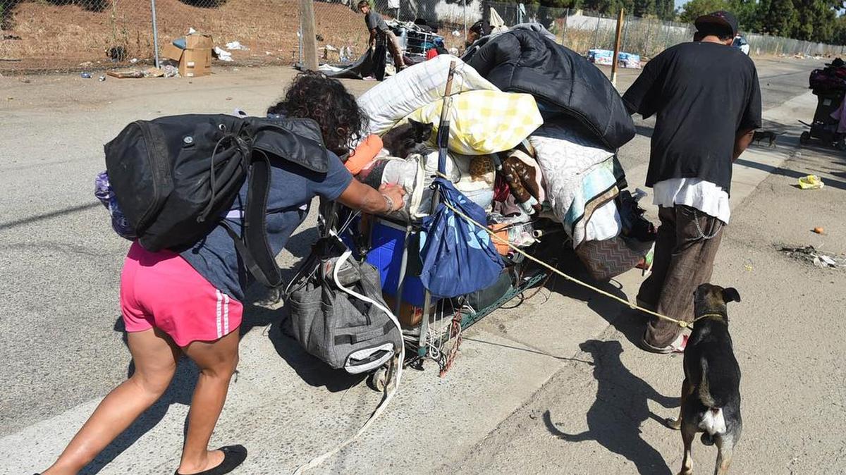 A homeless couple, with their dog and kitten, push their belongings – all they could pack on a makeshift cart – after being told to move on from a central Fresno alley, and after they were offered assistance on Aug. 14, 2018.