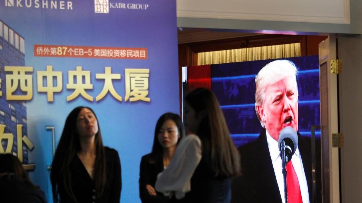 A projector screen shows footage of U.S. President Donald Trump as workers wait for investors at a reception desk during an event promoting EB-5 investment in a Kushner Companies development at a hotel in Shanghai, China, on Sunday. The sister of President Trump's son-in-law, Jared Kushner, has been courting Chinese investors using a much-criticized federal visa program that provides a path toward obtaining green cards.