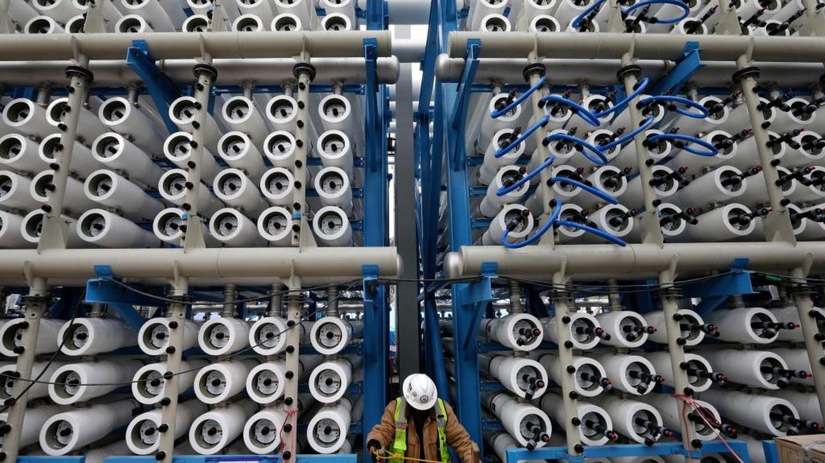 A worker in this 2015 photo climbs among some of the 2,000 pressure vessels used to convert seawater into fresh water through reverse osmosis in the desalination plant in Carlsbad. The developers of that plant have been awaiting approval for a second plant in Huntington Beach for nearly 20 years.