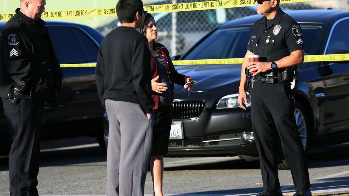 Police officers explain to a parent and her son that officials closed all Los Angeles Unified schools Tuesday after an email threat.