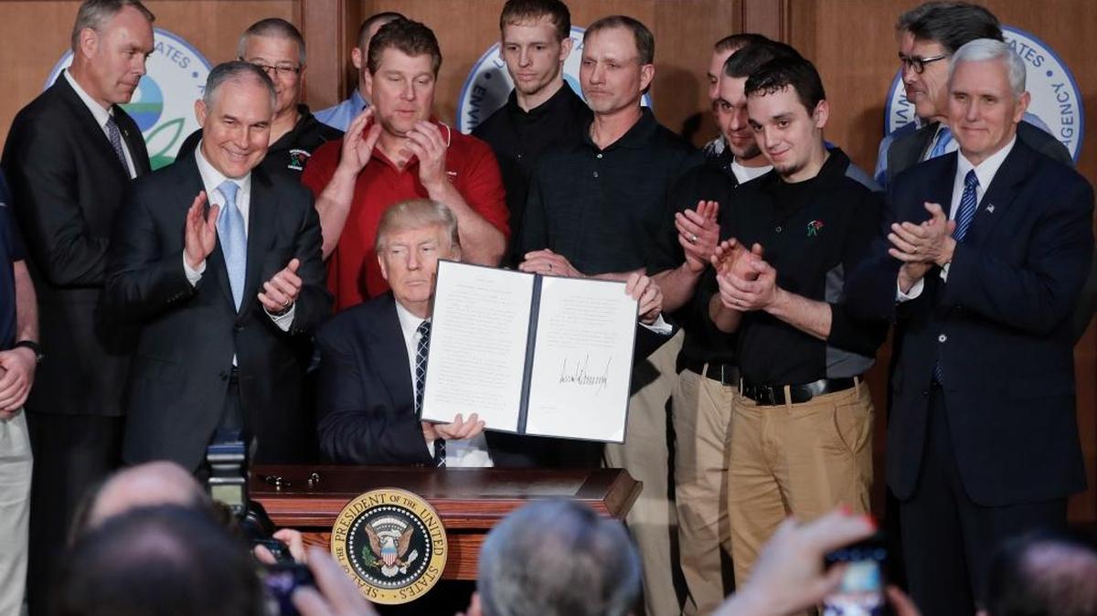 President Donald Trump, accompanied by coal miners and, from left, Interior Secretary Ryan Zinke; Environmental Protection Agency Administrator Scott Pruitt, second from right; Energy Secretary Rick Perry, and Vice President Mike Pence, far right, holds the Energy Independence Executive Order, Tuesday, March 28, 2017, at EPA headquarters in Washington, D.C.