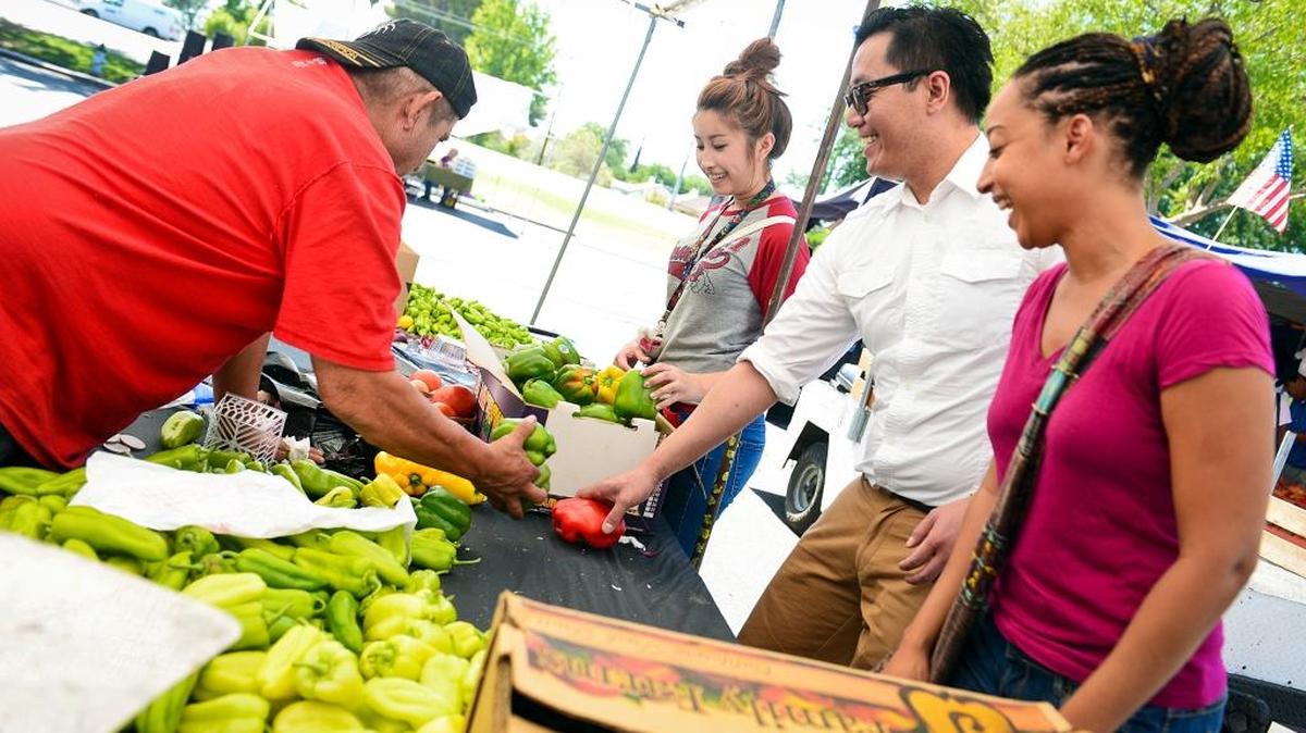 Rose Cardoso, Anoy Phuangsavath and Shoua Chang look over vegetables at the Manchester Center Farmers Market Friday, July 18, 2014. Health experts say that eating more vegetables will improve your health.