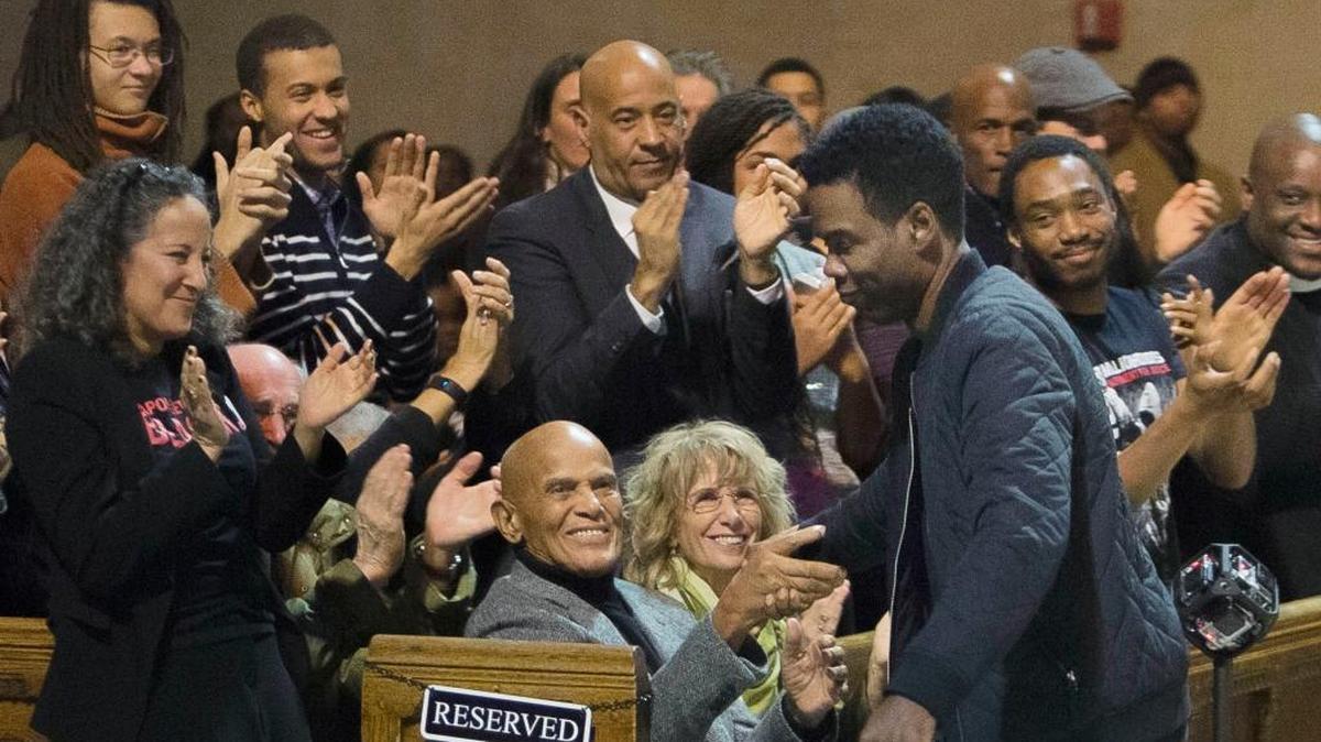 In this Monday, Jan. 18, 2016 photo, Comedian Chris Rock, center right, shakes hands with singer and social activist Harry Belafonte, center left, during an event celebrating the life and legacy of Dr. Martin Luther King Jr. at the Riverside Church in New York. Rock, who is scheduled to host the Oscars Feb. 28, has unveiled a new promotion for the broadcast, calling the ceremony "The White BET Awards." (AP Photo/Andres Kudacki)