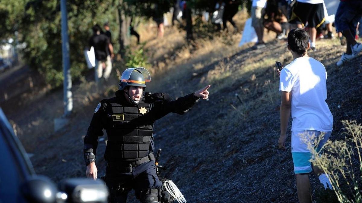 A California Highway Patrol officer blocks protesters from Highway 41 Saturday in Fresno. Marchers proceeded north along Blackstone Avenue after blocking the intersection, then, as they marched east along Bullard Avenue, attempted to march down the onramp to Highway 41 but were stopped by police in riot gear.
