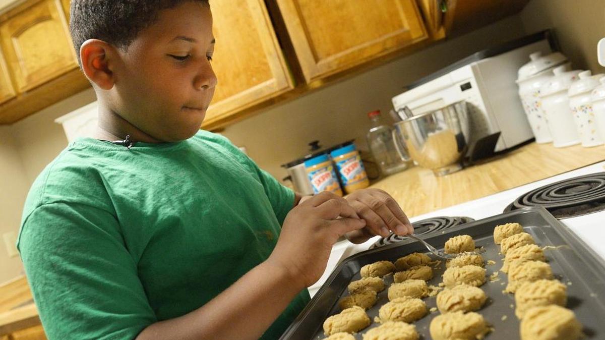 Jalen Bailey of Fresno prepares a batch of peanut butter cookies for the oven at his family’s home in this file photo from 2016.