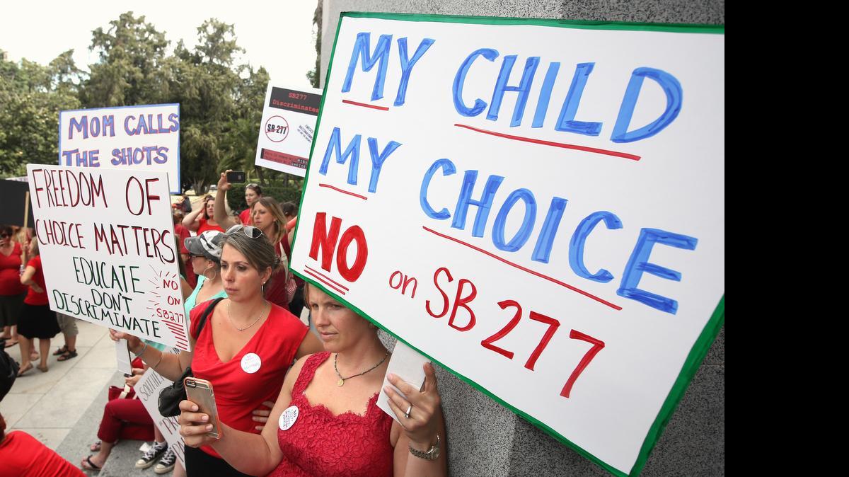 
Karman Willmer, left, and Shelby Messenger protest against SB277, a measure requiring California schoolchildren to get vaccinated, at a Capitol rally Tuesday in Sacramento. The bill would only allow children with a physician’s aproval to opt out of vaccinations needed to attend school.
