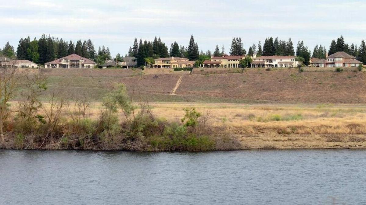 Large homes are seen on the bluffs above a pond near the San Joaquin River in north Fresno in May. The area is in crosshairs of homeowners and members of the public trying to agree on access to the river area.