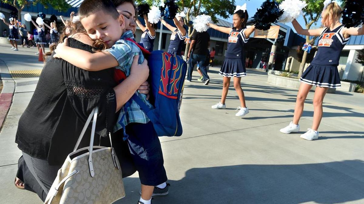 In his new school clothes and backpack, 5-year-old Matthew Diaz gets in one last, long goodbye with mom, Melissa Baca, before heading off to his first day of kindergarten at Harvest Elementary, Wednesday morning, Aug. 9, 2017.