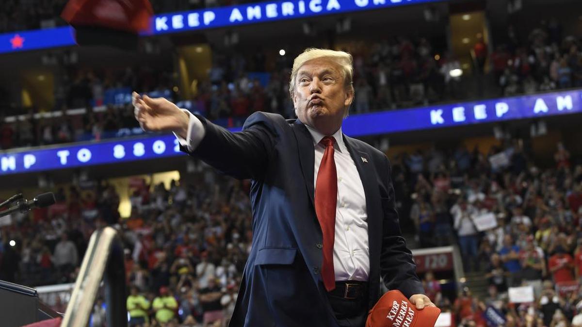 President Donald Trump throws a hat as he arrives to speak at a campaign rally in Sunrise, Fla., Tuesday, Nov. 26, 2019.