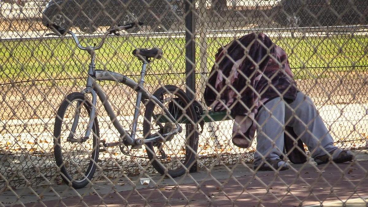 A homeless person sleeps under a blanket on a bench in the tennis court area of Dickey Playground in Fresno on Friday, Oct. 19, 2018. Measure P, the sales tax to benefit Fresno parks, will be decided by Fresno voters at the polls next week.