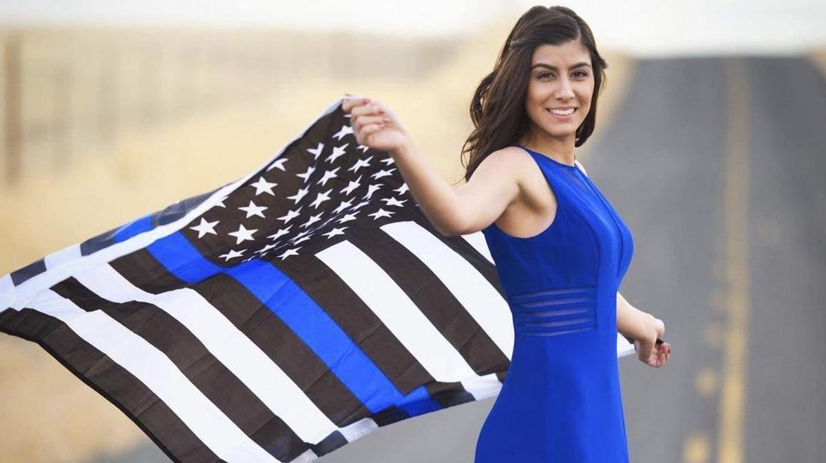 This portrait of Natalie Corona by Richard Laus shows the Davis police officer who was killed in the line of duty. Here she is shown waving the Thin Blue Line American Flag. The flag’s manufacturer describes it as a “testament to the valor of police officers across the country.”