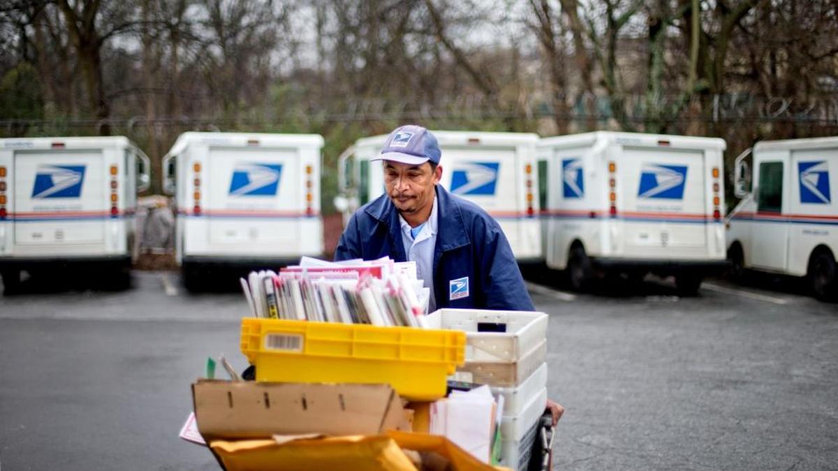 A U.S. Postal Service letter carrier gathers mail to load into his truck before making his delivery run in 2013.