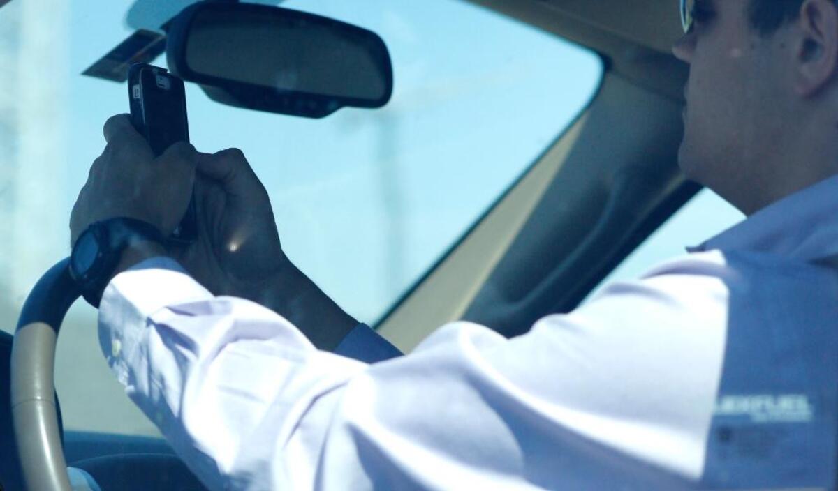 A man looks at his phone while driving down Woodall Rodgers Freeway in Dallas.