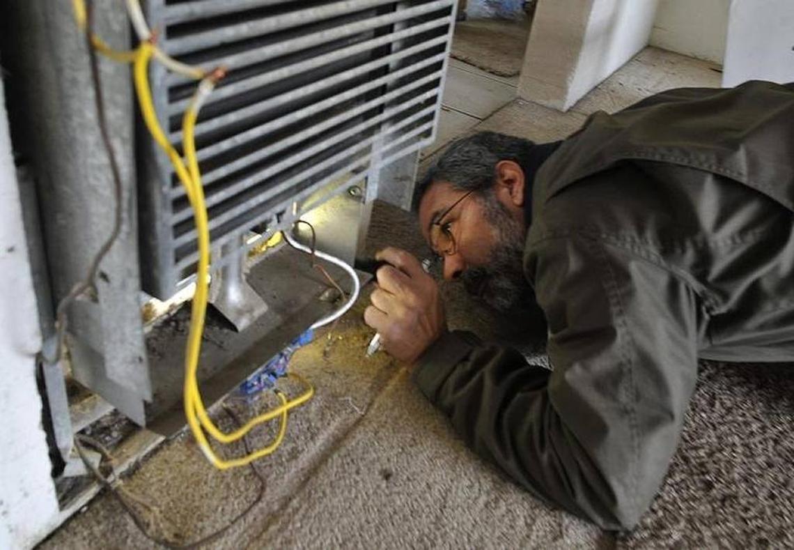 In 2016, city code enforcement inspector John Tanksley examines a broken heater — improperly hooked up and with bare wires exposed — at a Fresno apartment complex. The Fresno City Council approved a rental housing inspection program in 2017.