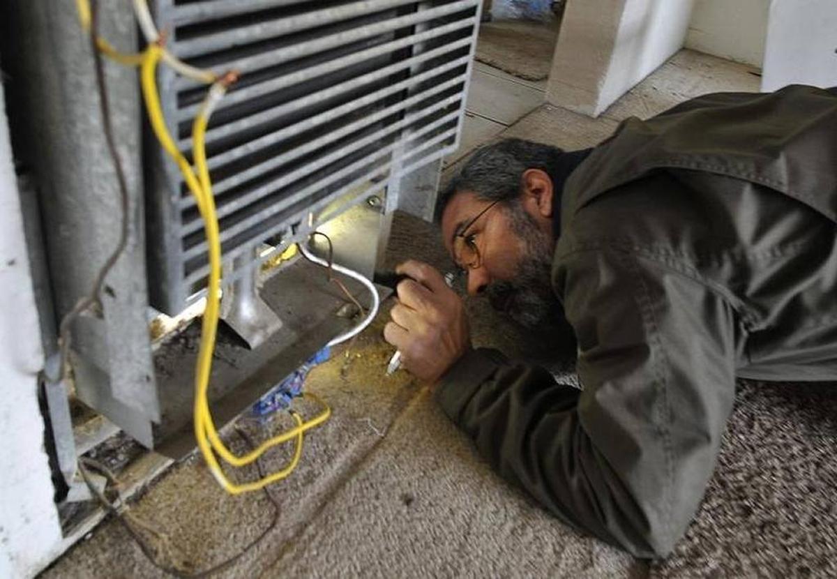 In 2016, city code enforcement inspector John Tanksley examines a broken heater — improperly hooked up and with bare wires exposed — at a Fresno apartment complex. The Fresno City Council approved a rental housing inspection program in 2017.