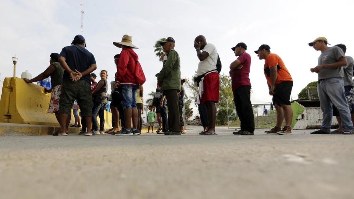 Latin American migrants seeking asylum in the United States line up for a meal provided by volunteers near an international bridge in Mexico, across the border from Texas, in a 2019 file photo.