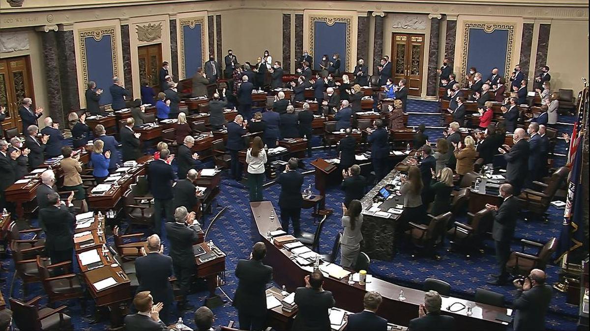 In this image from video, senators and staff give a standing ovation to U.S. Capitol Police offer Eugene Goodman, standing in the far back row, shortly before voting to award him the Congressional Gold Medal for his actions during the Jan. 6 riot, as the Senate took a break from the second impeachment trial of former President Donald Trump in the Senate at the U.S. Capitol in Washington, Friday, Feb. 12, 2021. (Senate Television via AP)