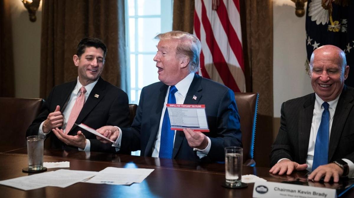 President Donald Trump, flanked by Speaker of the House Rep. Paul Ryan, R-Wis. and Chairman of the House Ways and Means Committee Rep. Kevin Brady, R-Texas, holds an example of what a new tax form may look like during a meeting on tax policy with Republican lawmakers at the White House on Thursday. Gordon Fake of Fresno says he will see a tax increase with the new formula.
