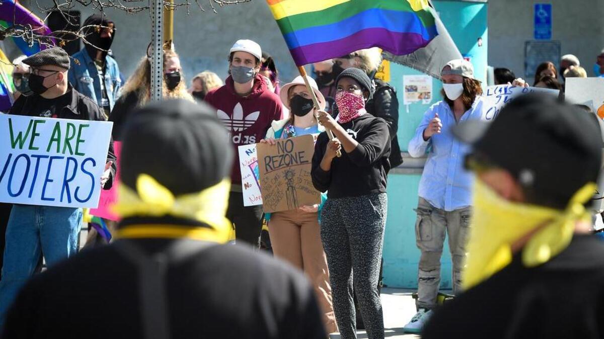 Lucy Schmidt, among around 200 protesting the sale of the historic Tower Theater to Adventure Community Church, waves her rainbow flag across the street from a small group of protestors wearing the colors and insignias of the Proud Boys and Oath Keepers, standing in front of the theater, March 21, 2021.