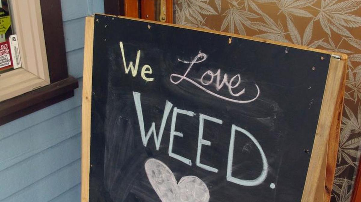 A sign stands outside Rainforest Farms, a retail marijuana shop in downtown Juneau, Alaska, one of many states lured by tax money from marijuana.