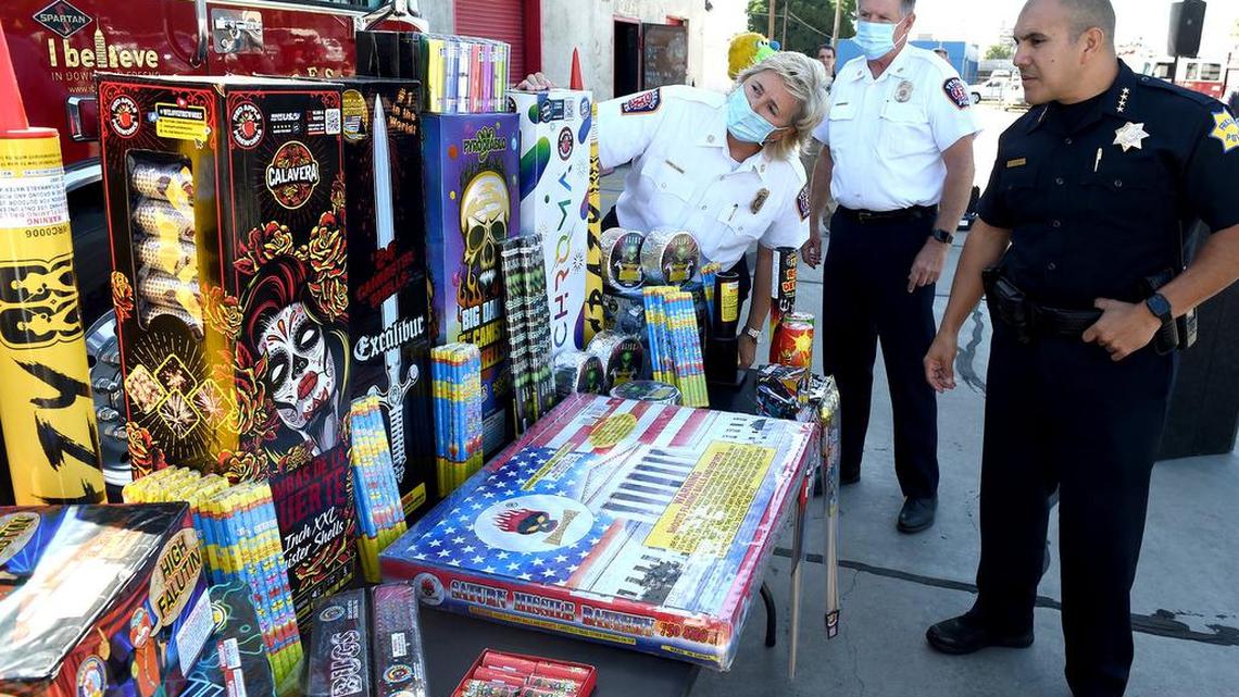 Fresno Fire Chief Kerri Donis, left, Deputy Fire Chief Ted Semonious, center and Fresno Police chief Paco Balderrama look over a tableful of illegal fireworks after a July 2021 press conference to address the increase usage of illegal fireworks on the eve of the Fourth of July holiday.