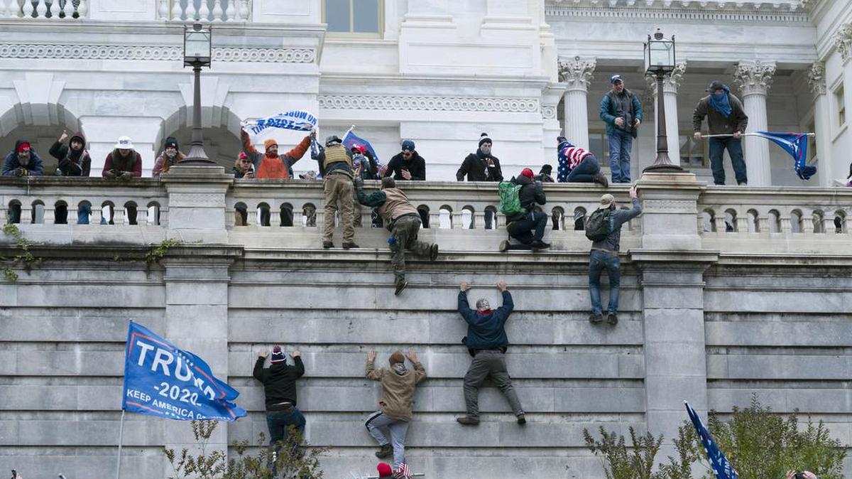 Violent insurrectionists loyal to President Donald Trump scale the west wall of the the U.S. Capitol in Washington on Jan. 6. In the nearly nine months since, federal agents have managed to track down and arrest more than 600 people across the U.S. believed to have joined in the riot at the Capitol. Getting those cases swiftly to trial is turning out to be an even more difficult task.