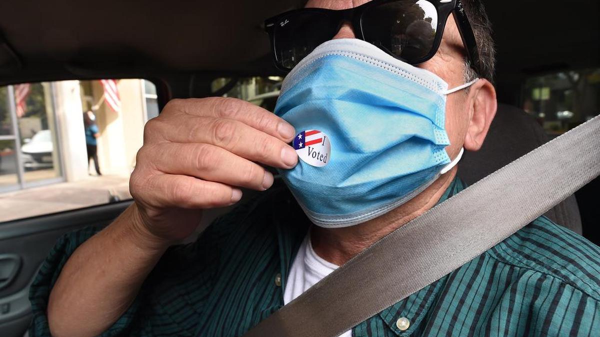 Rick Rendon of Fresno puts his “I Voted” sticker on his face mask after dropping off his ballot at the Fresno County Elections Office ballot box, Tuesday Oct. 6, 2020.