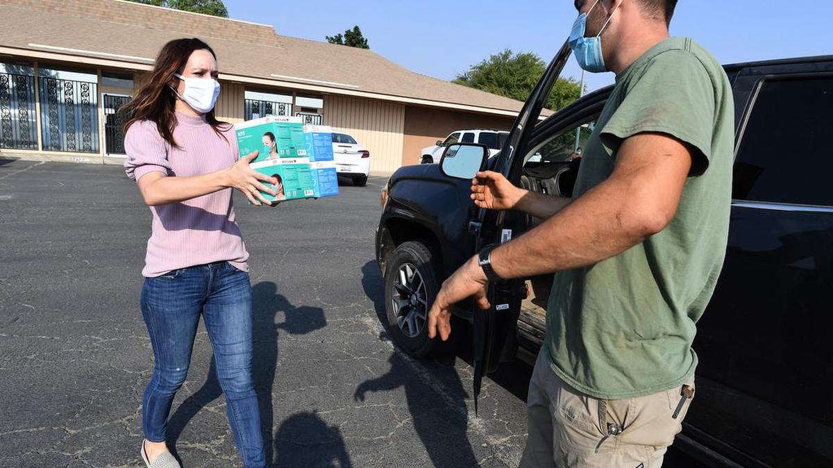 Kayleena Speakman, of the Fresno County Farm Bureau, gives a supply of N95 face masks to Biola farmer Donovan Failla, during a mask event earlier this month. Farm-worker safety is a priority as over 300,000 N95 masks were given to ag community in two weeks, according to Fresno County Farm Bureau CEO Ryan Jacobson.