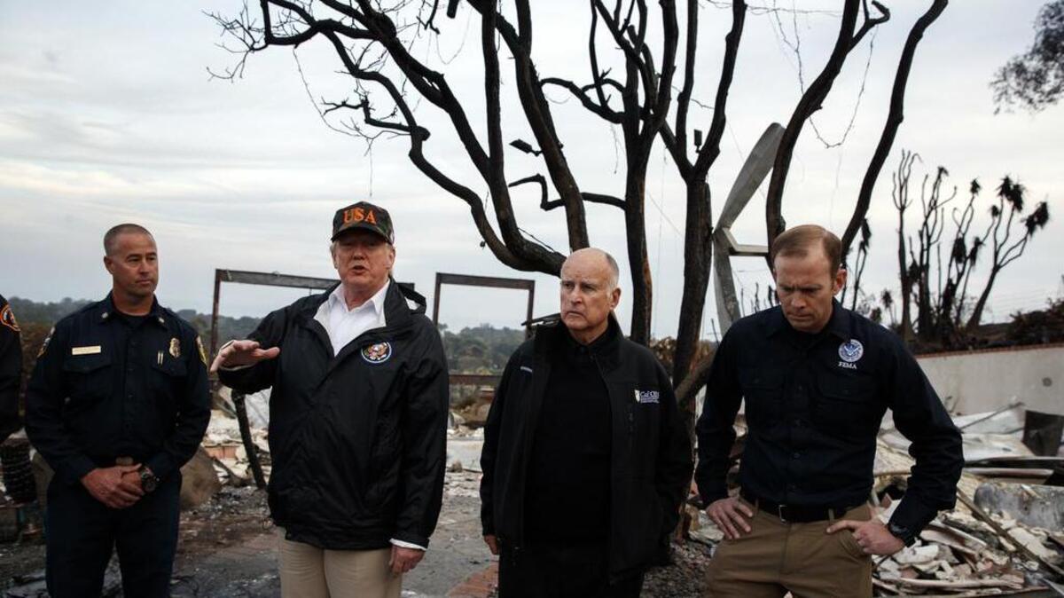 President Donald Trump visits a neighborhood impacted by the Woolsey Fire, Saturday, Nov. 17, 2018, in Malibu, Calif. At right is FEMA Administrator Brock Long and second from right is California Gov. Jerry Brown.