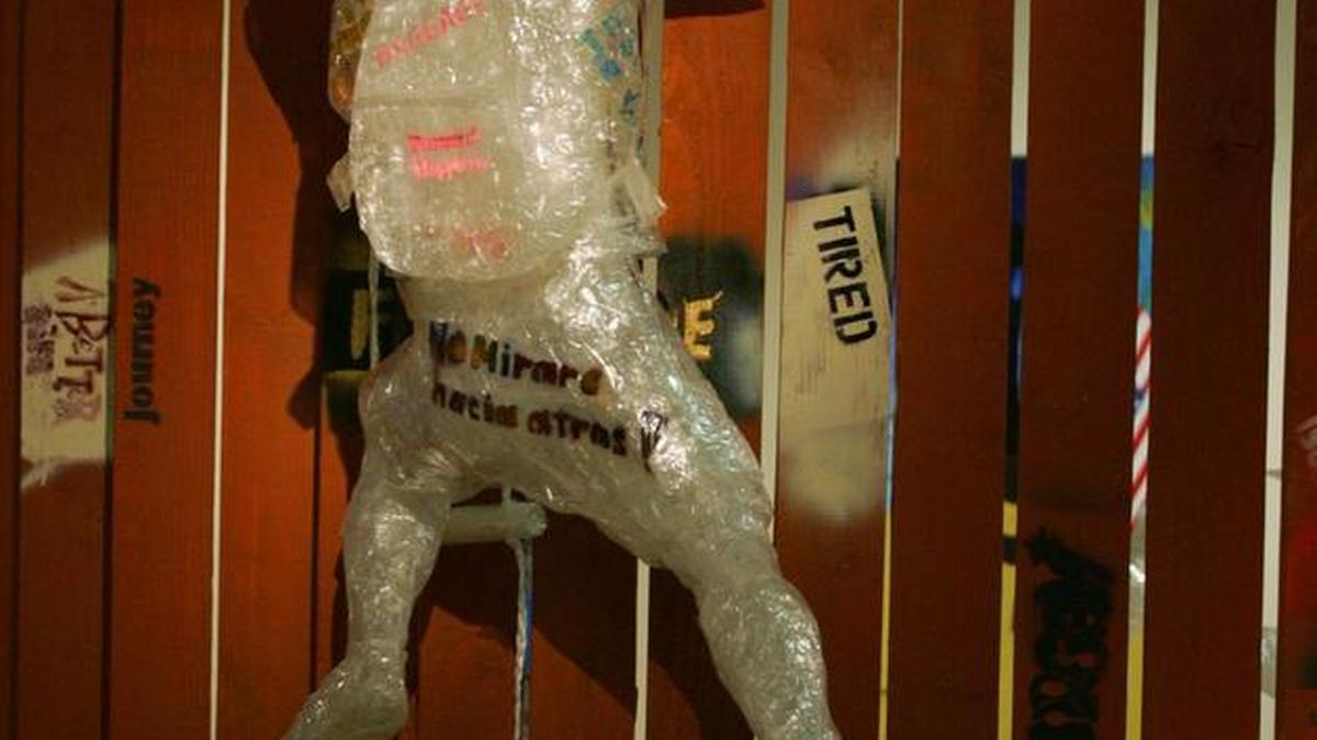 An immigrant climbing the US/Mexico border wall is depicted in this art piece by McLane High School students, one of many put on display at Arte Americas.
