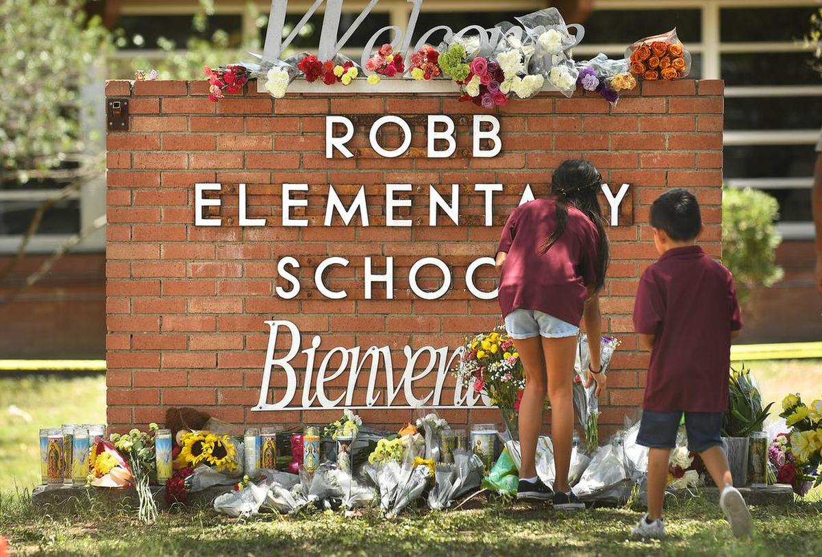 Family members who lost a sibling to a gunman’s shooting rampage place flowers outside Robb Elementary School in Uvalde, Texas, on May 25, 2022. (Wally Skalij/Los Angeles Times/TNS)
