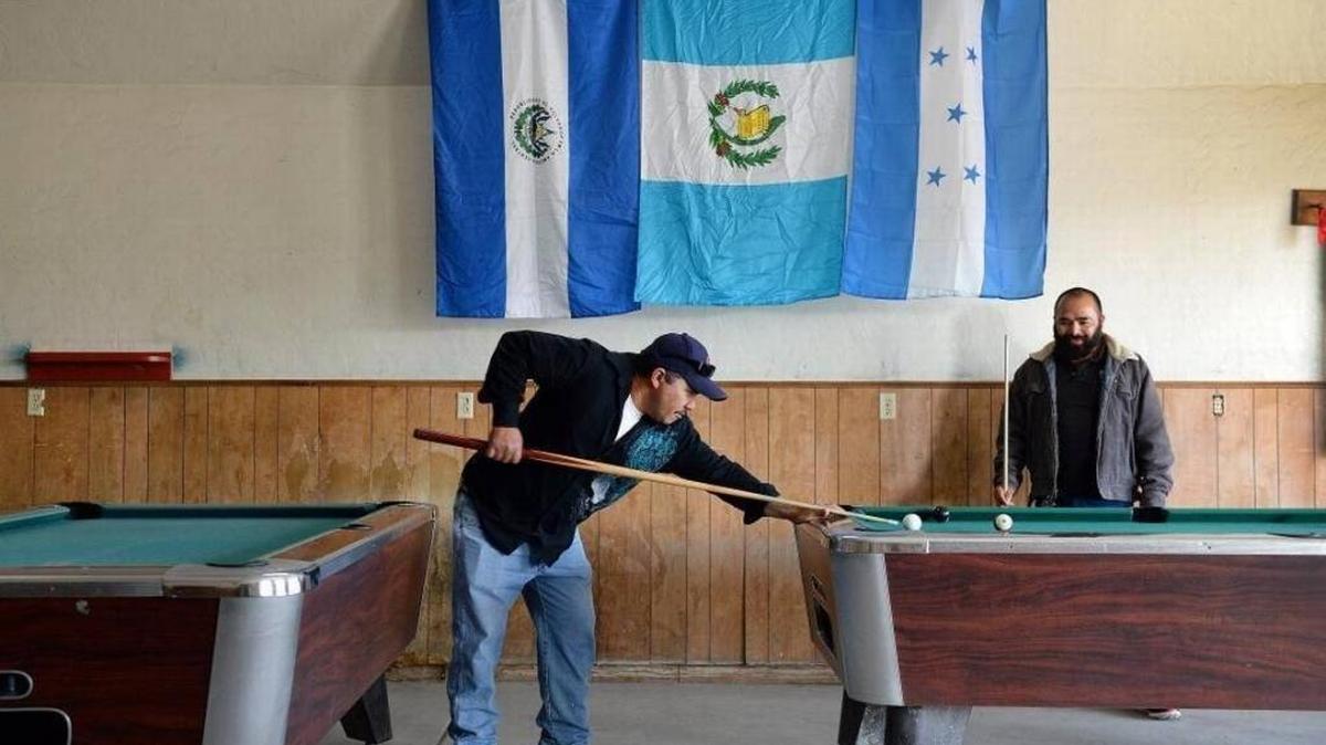 Mendota residents Jose Velasquez, left, and Oscar Lopez, both Salvadoran immigrants, play billiards below the flags of El Salvador, from left, Guatemala, and Honduras at Westside Pool Hall in Mendota on Jan. 12. Mendota city officials say that over half of the city’s residents have Salvadoran roots. Many of those are recipients of a temporary protection from deportation, which the Trump administration announced ended last week.