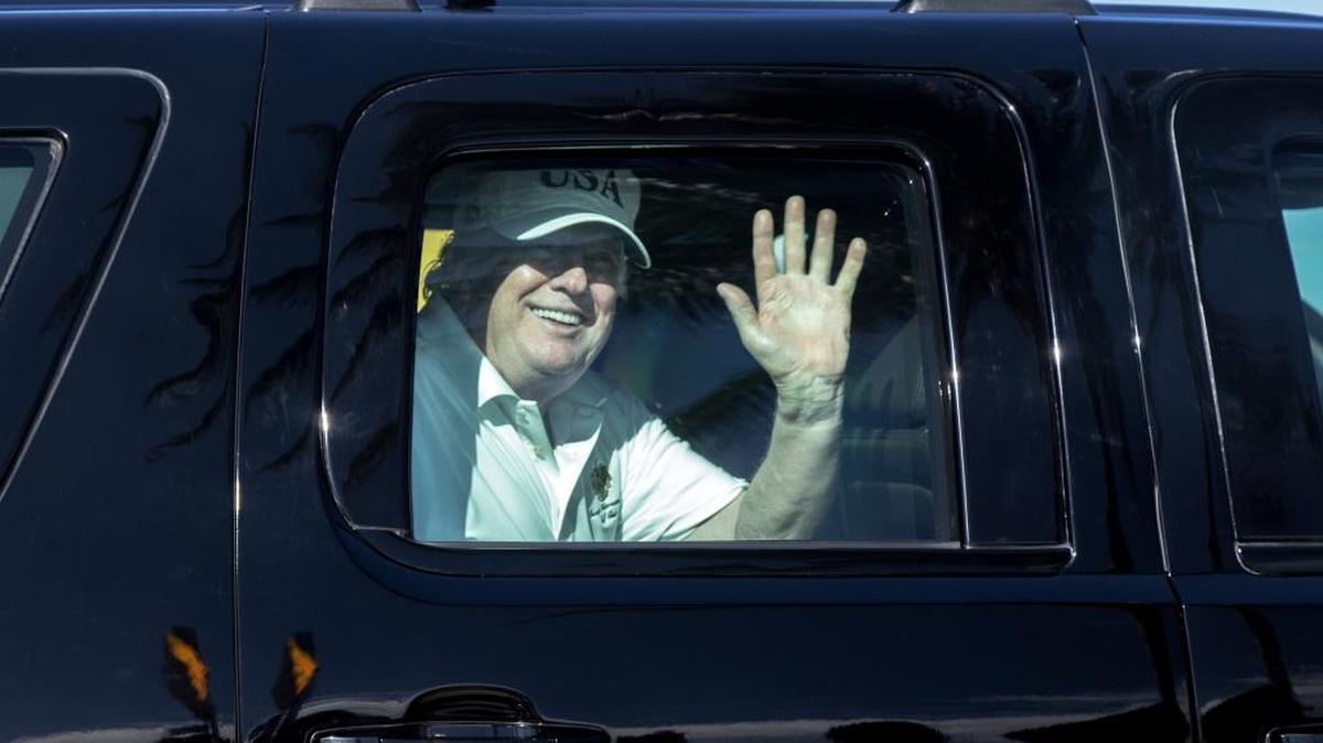 President Donald Trump waves from his motorcade traveling to Mar-a-Lago from Trump International Golf Club on Thursday in West Palm Beach, Fla.