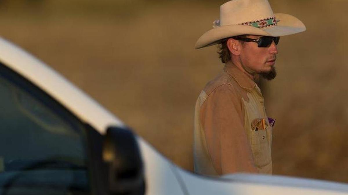 Johnny Langendorff, who he said pursued a suspect of a deadly church shooting, waits to be picked up from the scene where the suspect was found dead near the intersection of FM 539 and Sandy Elm Road in Guadalupe County, Texas Sunday.