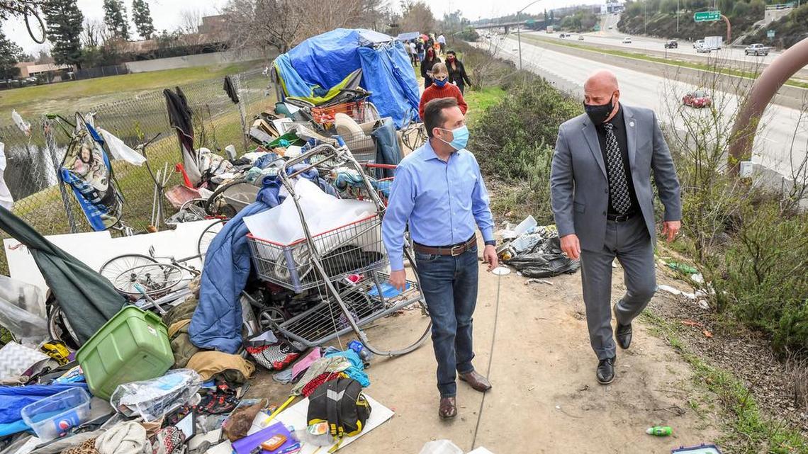 Fresno Mayor Jerry Dyer talks with Fresno Housing Authority commissioner Cary Catalano while touring a homeless encampment along Highway 41 near Bullard Avenue in Fresno on Thursday, Feb. 11, 2021. Mayor Dyer has spearheaded Project Off-Ramp, a partnership between the city, Caltrans, the CHP and the Poverello House to clean up the freeways around the city and find housing for people living in encampments.