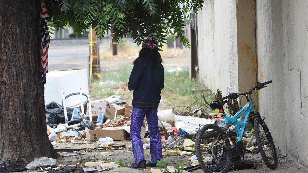 A homeless woman among refuse along the side of the old City Motel on Golden State in Fresno one recent morning. The motel is one that would be targeted by Fresno City Councilman Miguel Arias's proposal to create a non-transient motel inspection program for motels with code enforcement and health and safety issues.
