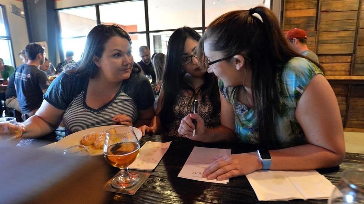 From left, Nicole Roland, 30, Erica Mardirosian, 37, and Sara Smith, 30, all of Fresno, discuss a question during Pub Quiz night at House Pendragon in Clovis, on July 5, 2016.